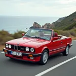 BMW E30 Cabrio fährt auf einer malerischen Küstenstraße