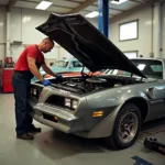 Wartungsarbeiten an einem 1978 Pontiac Firebird: Ein Mechaniker führt routinemäßige Wartungsarbeiten wie Ölwechsel, Zündkerzenprüfung und Bremskontrolle durch.