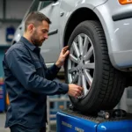 Ein Kfz-Mechaniker bedient eine Auswuchtmaschine in der Werkstatt, um die Unwucht an einem Reifen zu messen und zu korrigieren.