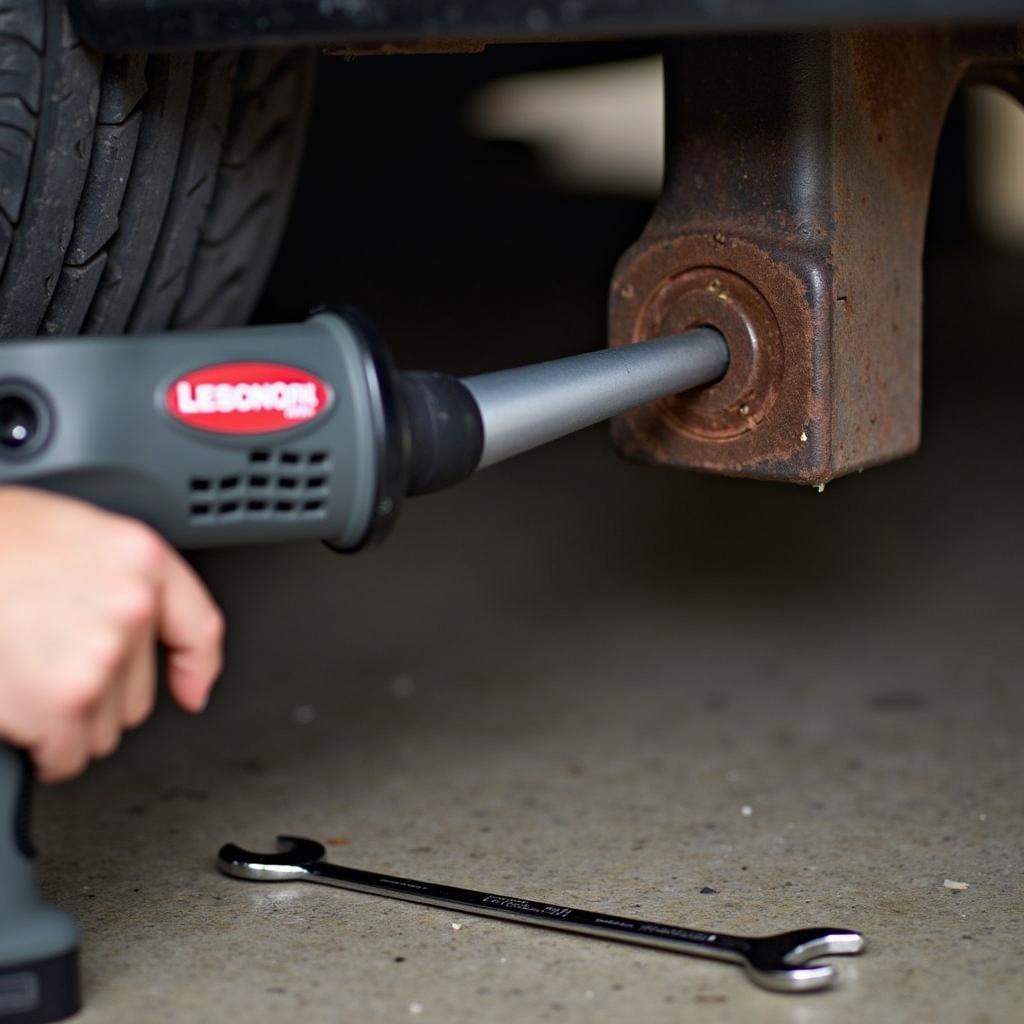 Mechaniker löst festsitzende Schrauben am Auto mit einem Handgebläse.